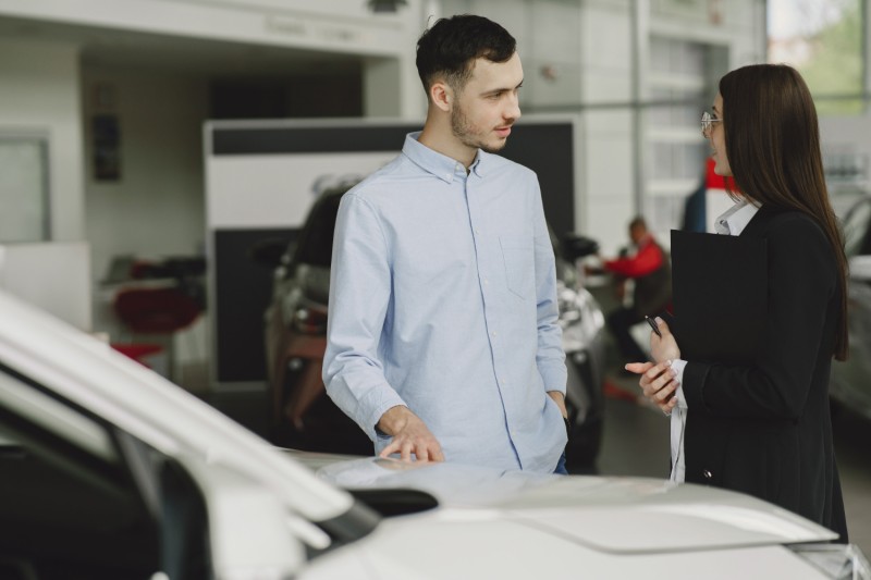 Man talking to a woman in a used car sales room